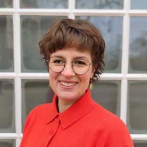 Frau mit braunen Haaren, Brille und einem roten Oberteil